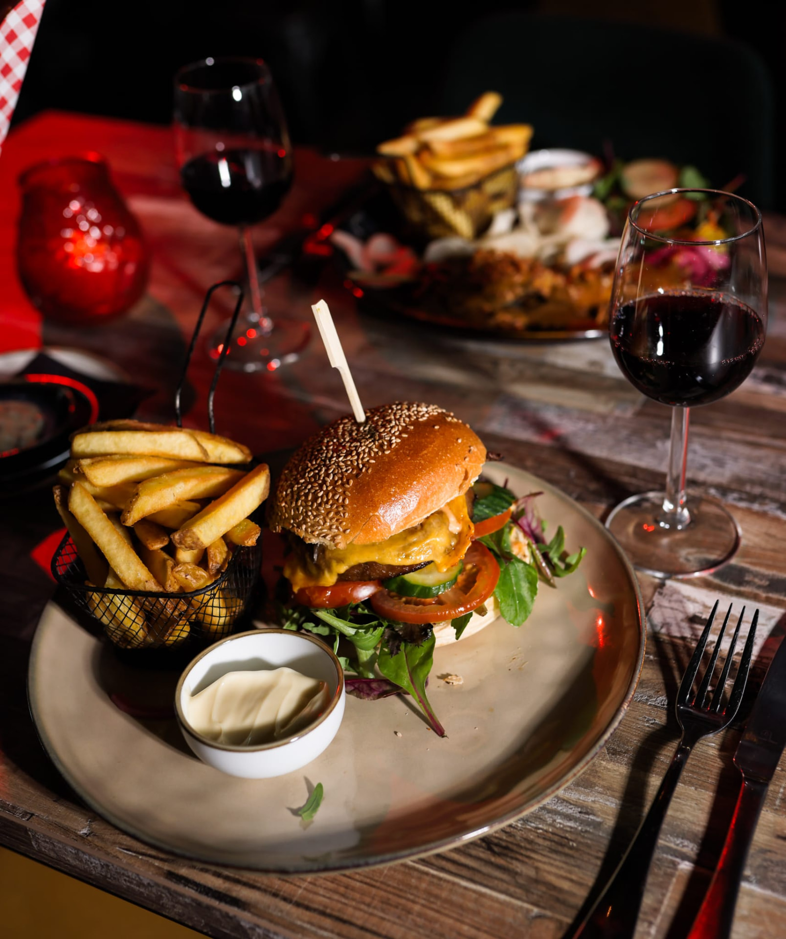 Burger met friet en een glas rode wijn aan tafel bij Het Plantsoen