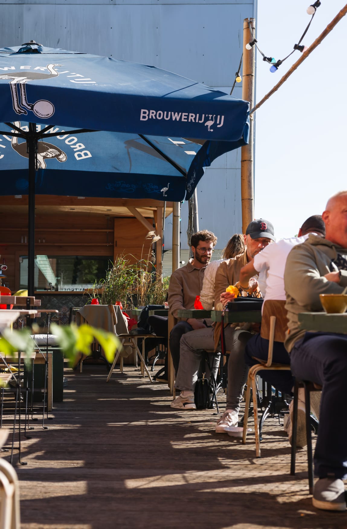 Gasten aan tafel op het zonnige terras van Het Plantsoen